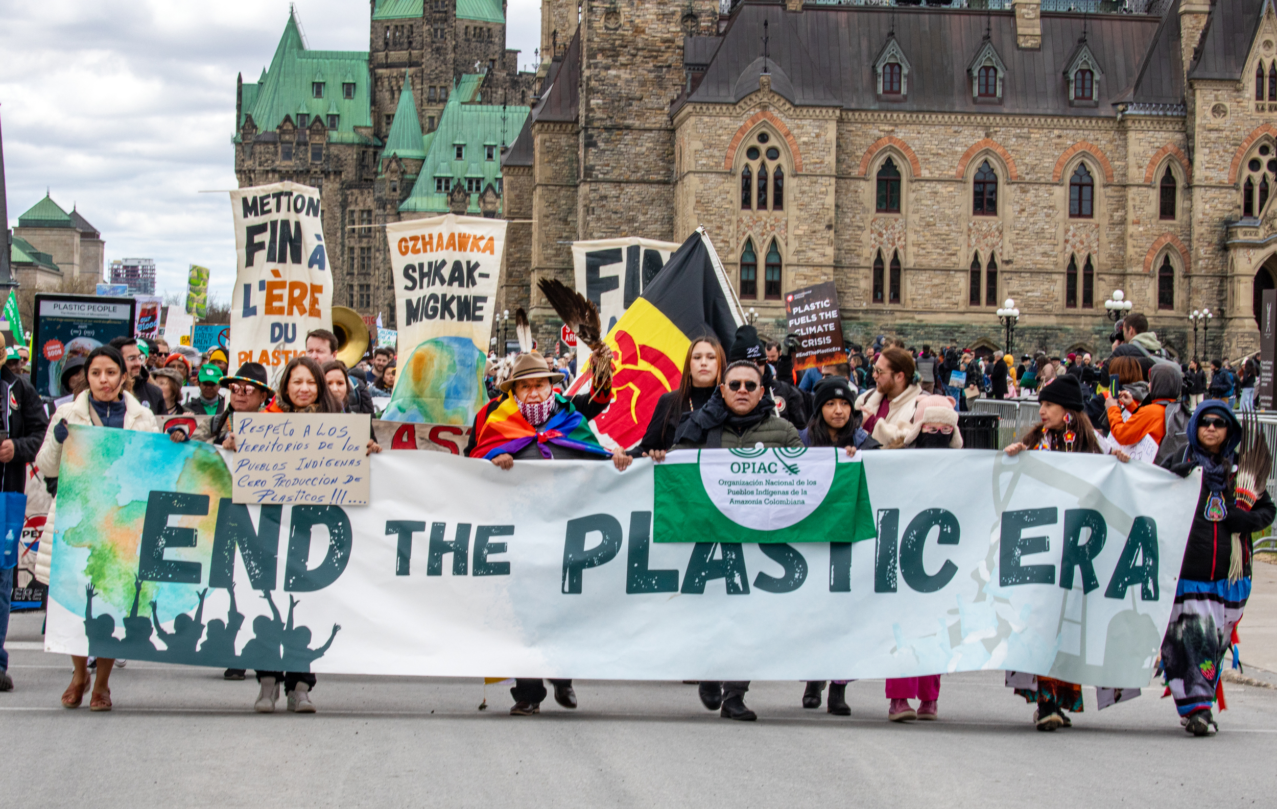 Protestors walk behind a banner that says 'End the plastic era'