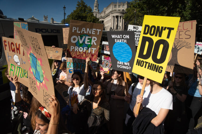 Protestors carry placards saying 'Don't do nothing' and 'Planet over profit'