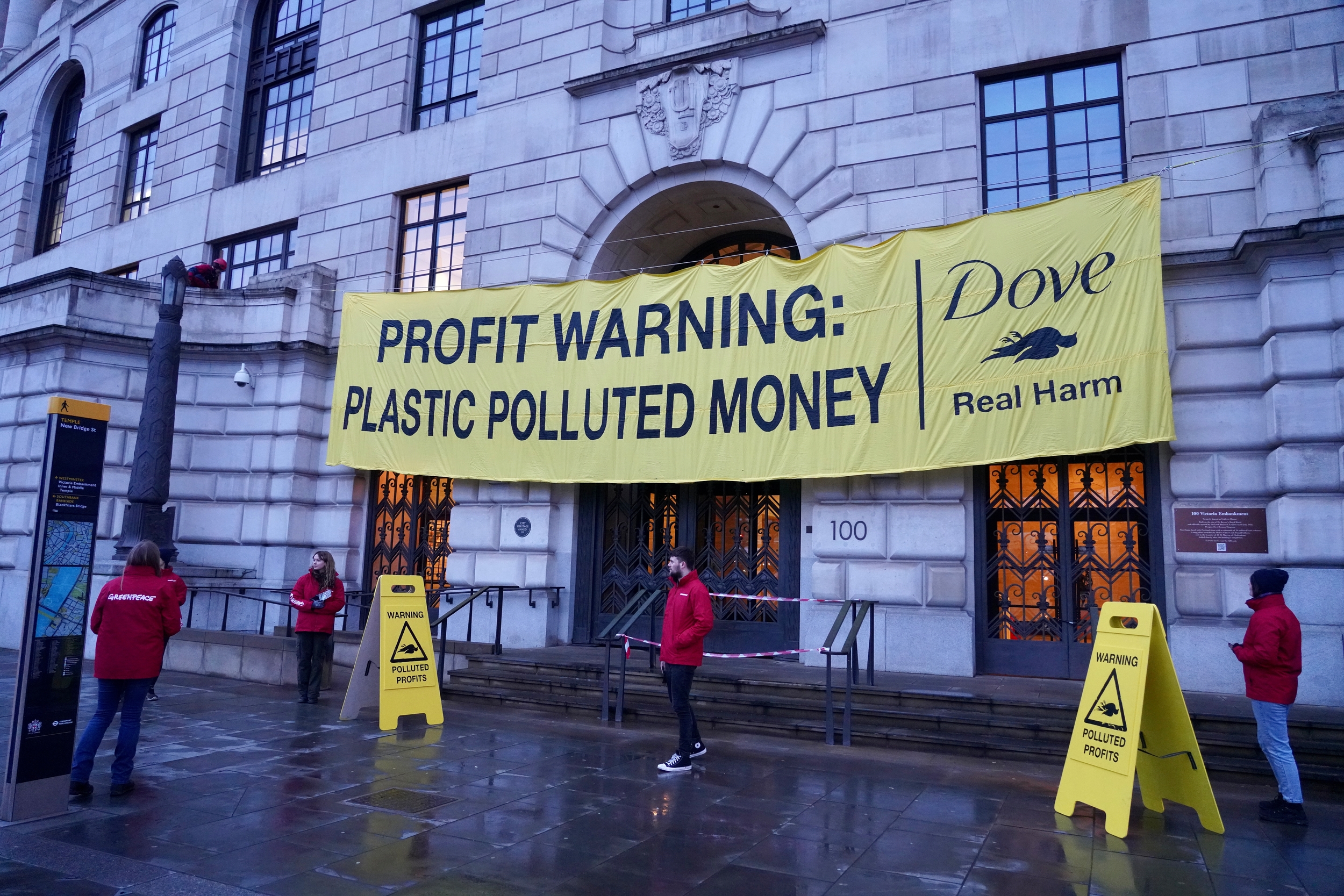 Activists outside the grand entrance to Unilever's London office display a banner that says 'profit warning: plastic polluted money'.