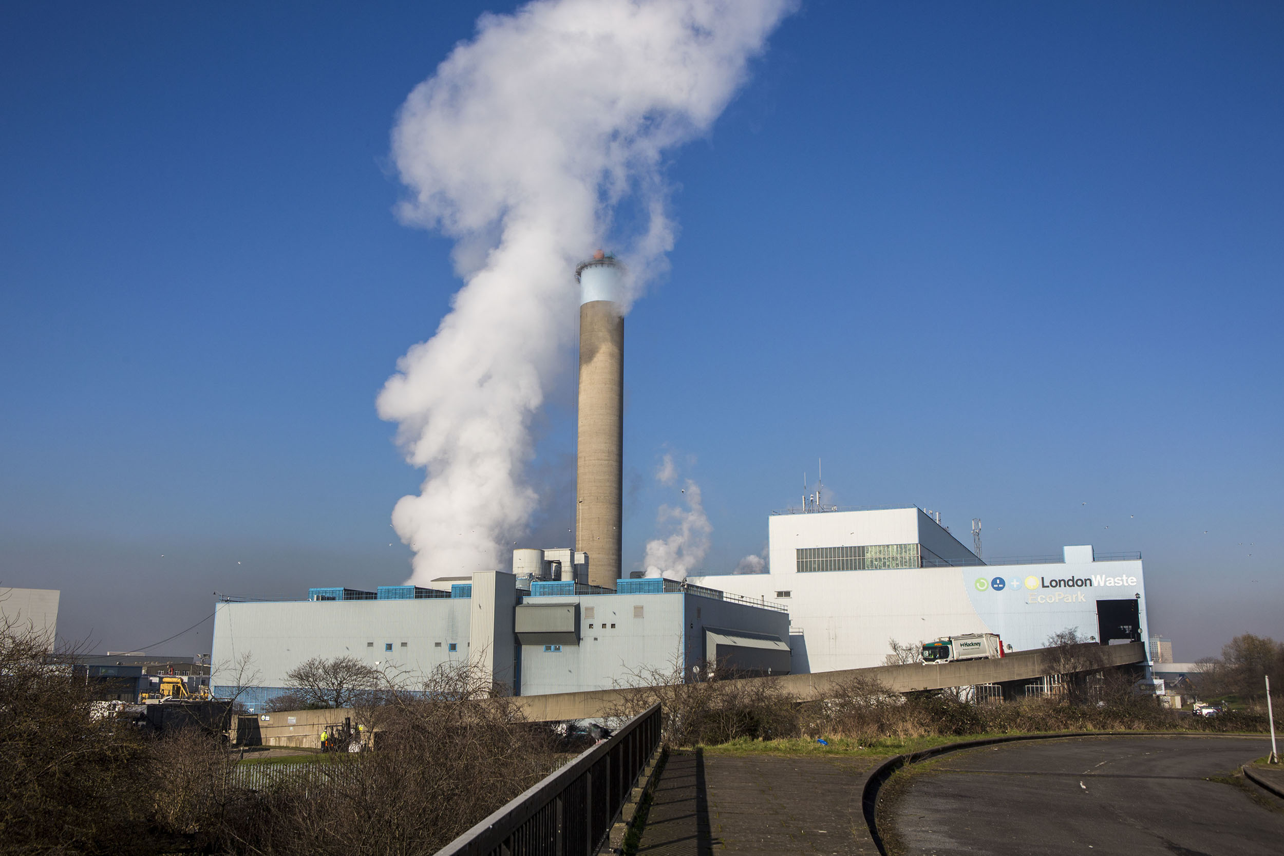 Steam bellows from a large chimney in an industrial waste site